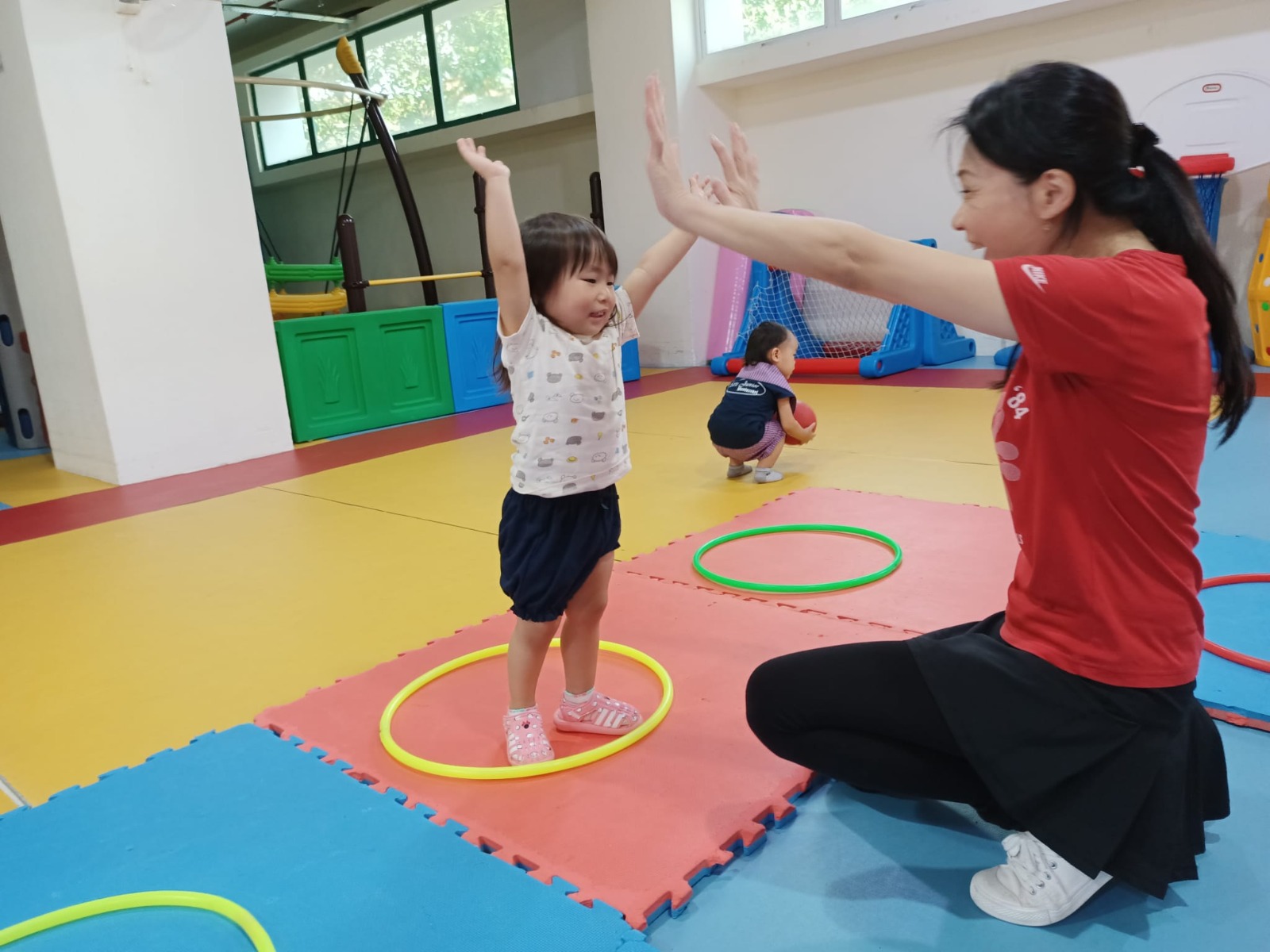 A teacher and child playing with hoops in the gym