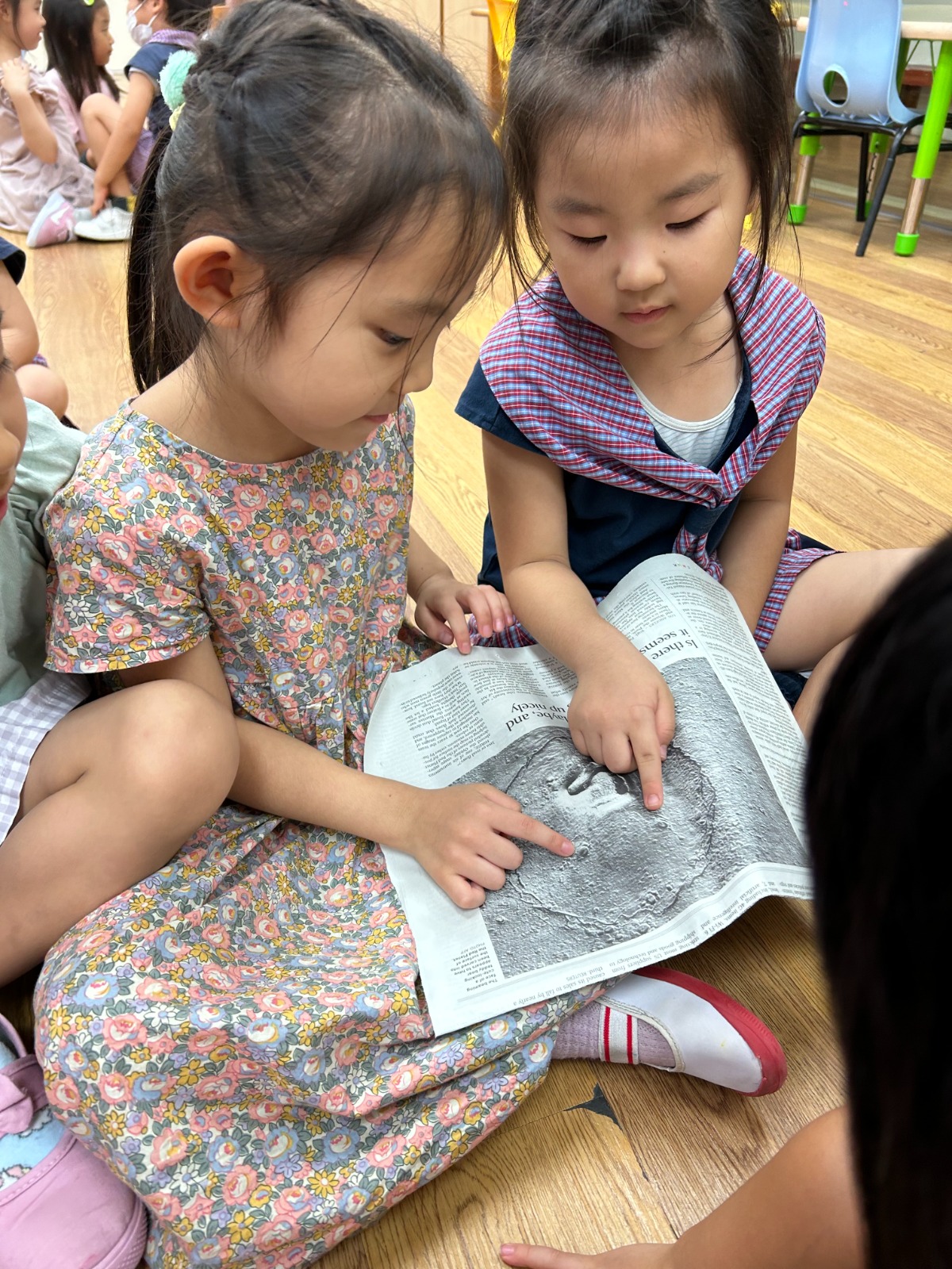 Children exploring a newspaper picture of the moon