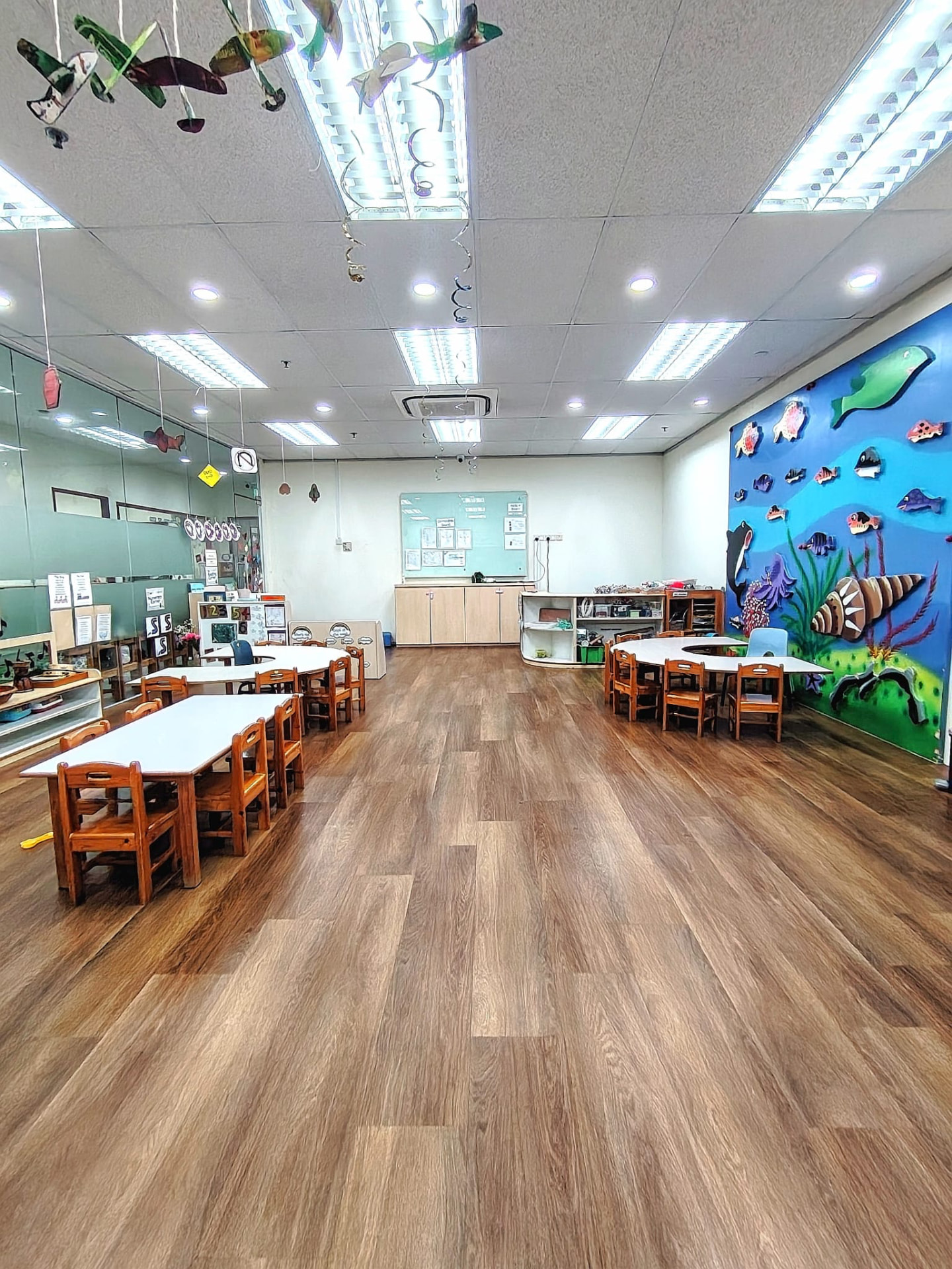 Arts Junior Montessori classroom with child-sized tables and an ocean mural